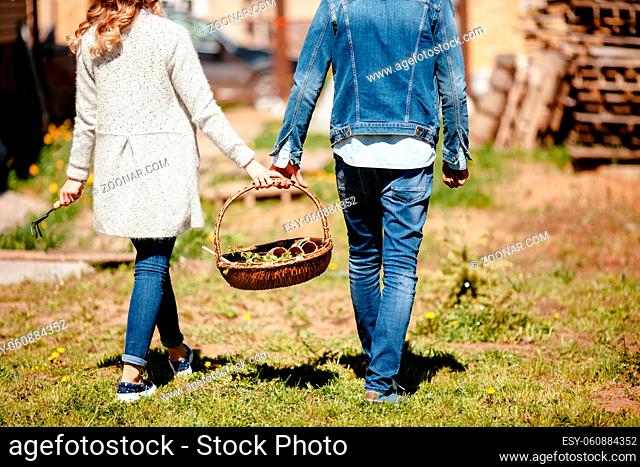 young couple carries a basket with seedlings in casual clothes