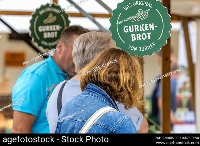 05 August 2023, Brandenburg, Golßen: At a sales booth at the Spreewald Gherkin Day in Golßen, visitors buy gherkin bread from a regional baker