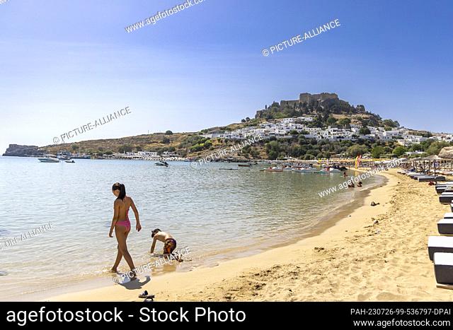 26 July 2023, Greece, Lindos: Tourists continue to be on the beach in Lindos, about 10 kilometers from the fires in the southeast