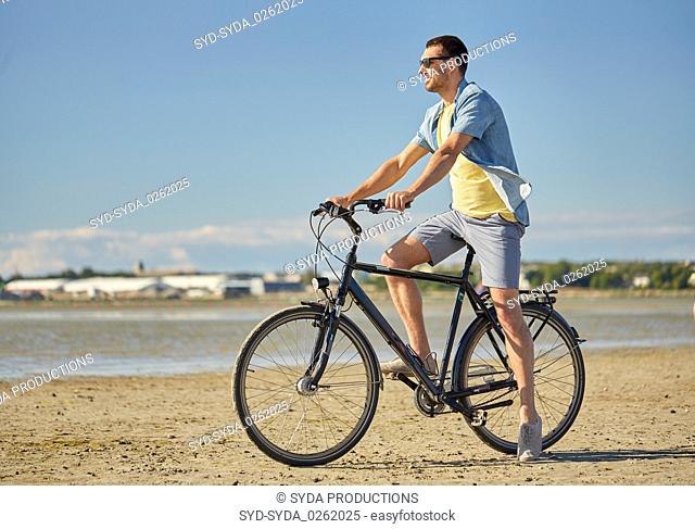 happy man riding bicycle along summer beach