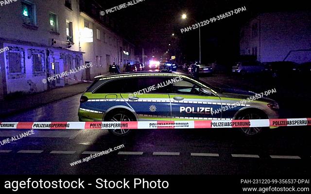 19 December 2023, Saarland, Neunkirchen: Police officers are deployed at a crime scene secured with barrier tape outside a pub