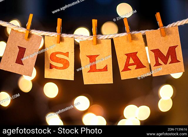The word ISLAM printed on clothespin clipped cards in front of defocused glowing lights
