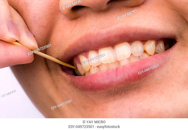 Asian woman clean her teeth from food stuck her teeth with bamboo wood toothpick after breakfast, lunch, dinner. Personal dental care with Asian style