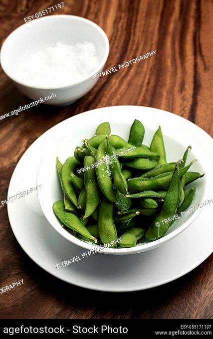 organic edamame beans snack in bowl on wooden table with sea salt