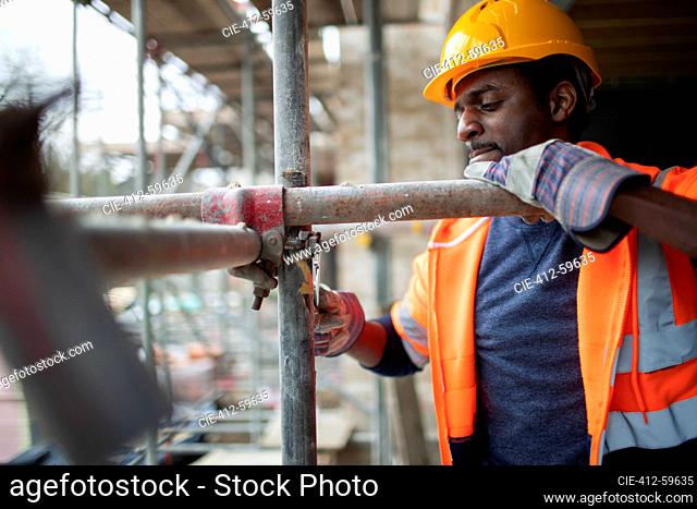 Male construction worker assembling scaffolding at construction site