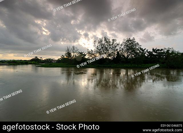 Reflection of mangrove trees at river in dark raining cloudy day