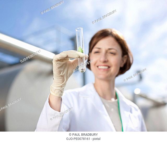 Scientist examining test tube outdoors
