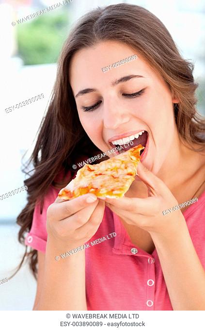 A woman holding a piece of pizza to her mouth as she is about to eat