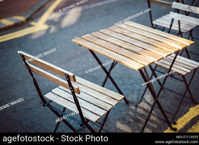 Wooden café table and chairs on street, Brighton, England