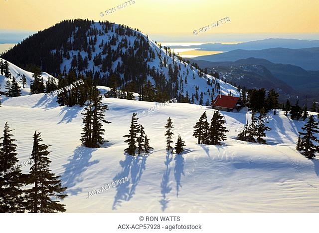The sun sets on Mt. Steele cabin in Tetrahedron Provincial park on the Sunshine Coast with the Strait of Georgia and Vancouver Island as backdrop