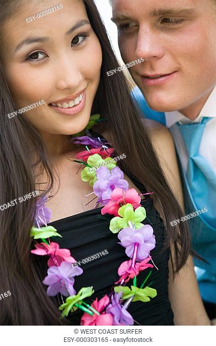 Well-dressed teenage couple wearing leis outside school dance