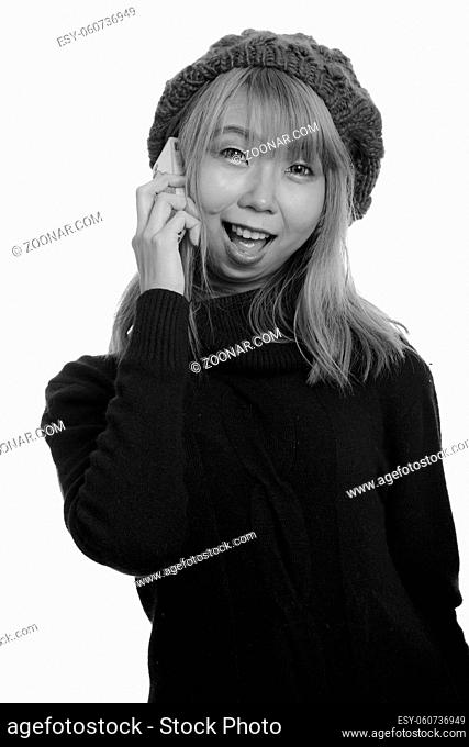 Studio shot of young Asian woman wearing turtleneck sweater isolated against white background in black and white