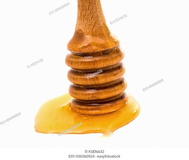 Honey dripping from a wooden honey dipper on white background