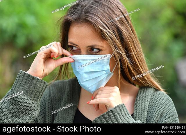 Topic image Corona: Correct fit - a young woman puts on protective mask, face mask, community mask on April 24th, 2020. | usage worldwide