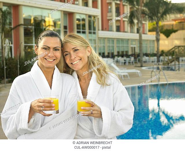 Two women by hotel pool with juice