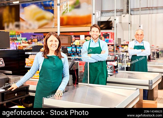 Freundliches Verkäufer Kollegen Team mit Schürze an der Kasse im Supermarkt