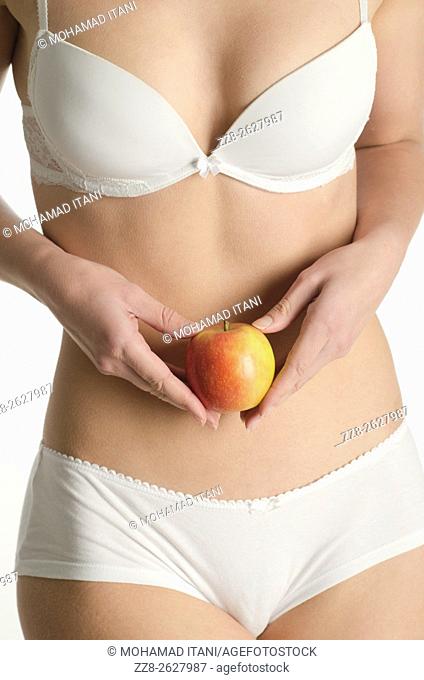 Close up of a young woman in underwear holding an apple
