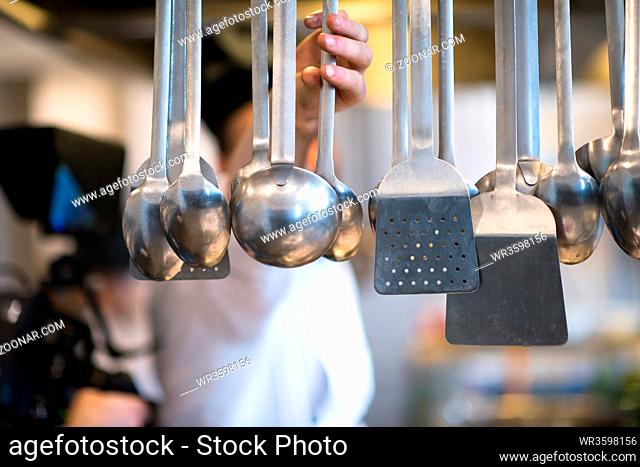 professional Cooking utensils hanging in a restaurant kitchen