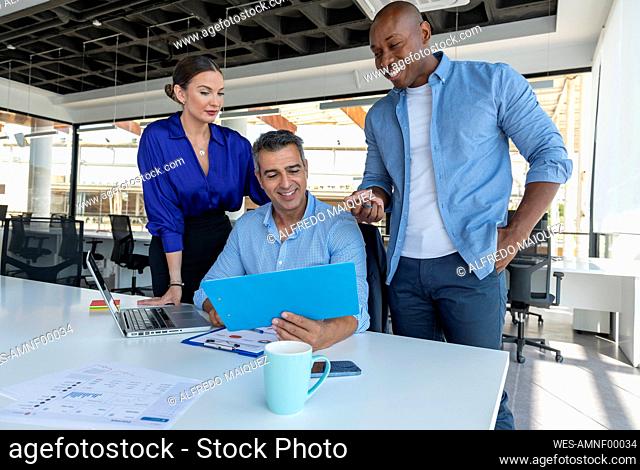 Smiling businessman discussing with colleagues in meeting at work place