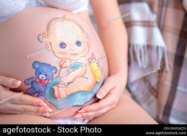 Cute drawing on the stomach of a pregnant woman in the form of a cheerful baby