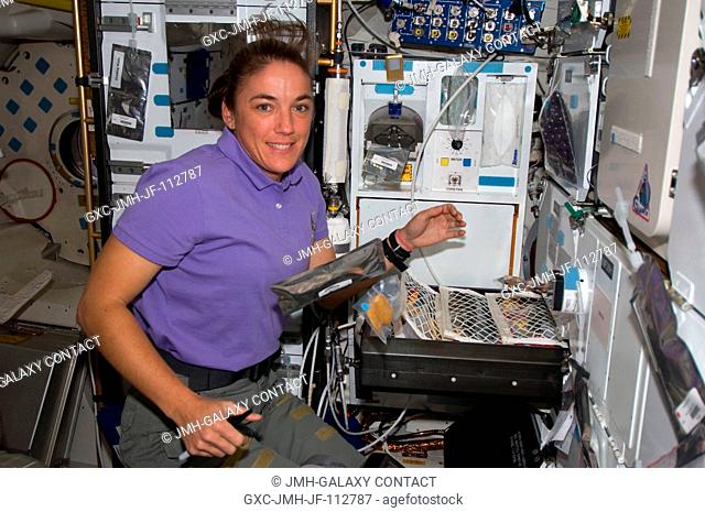 Astronaut Heidemarie Stefanyshyn-Piper, STS-126 mission specialist, takes a moment for a photo as she makes her selection for a meal at the galley on the...
