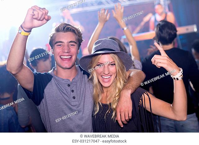 Portrait of cheerful friends with arm around at nightclub