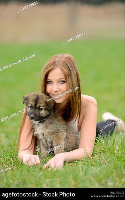 Young woman with a mixed breed dog puppy in garden