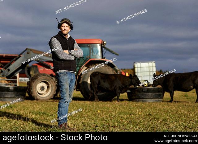 Farmer standing in field with tractor in background