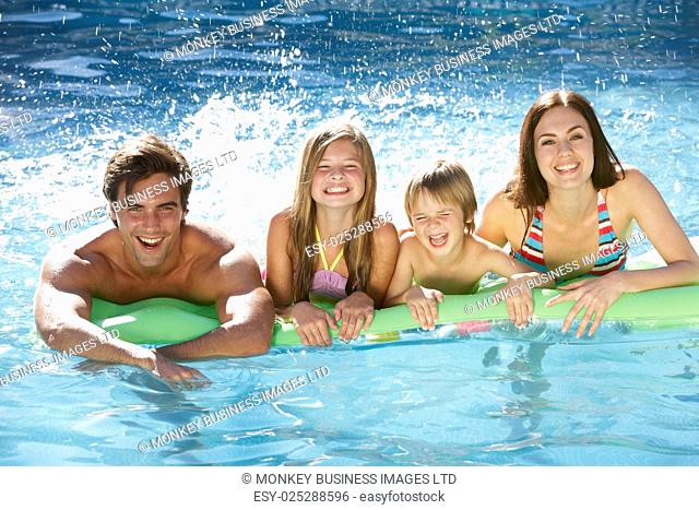 Family Relaxing In Swimming Pool Together