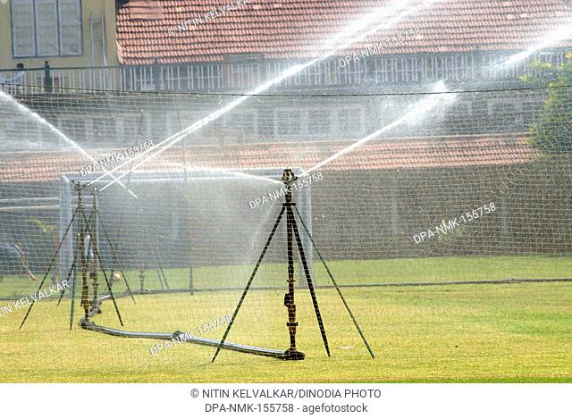 Sprinkler system sprinkling water for lush green grass in garden of Bombay Gymkhana at Azad Maidan ; Bombay Mumbai ; Maharashtra ; India