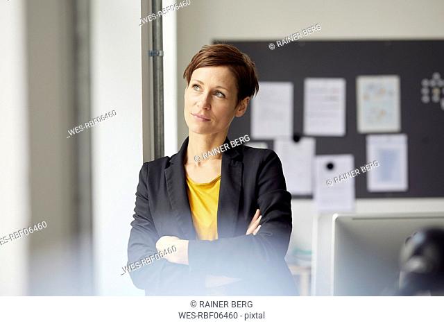 Attractive businesswoman standing in office with arms crossed