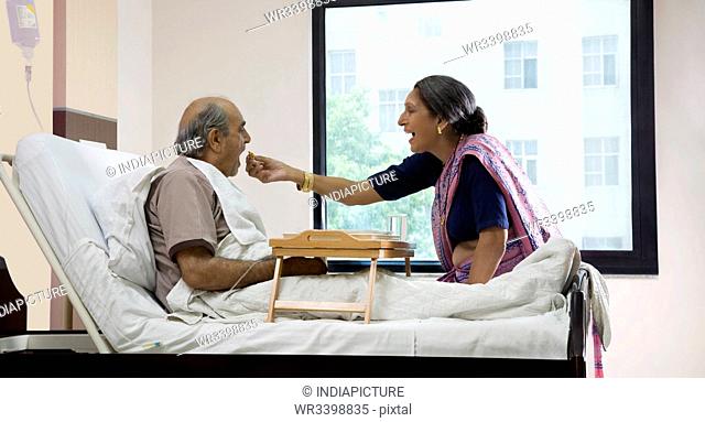 Wife feeding her husband in a hospital