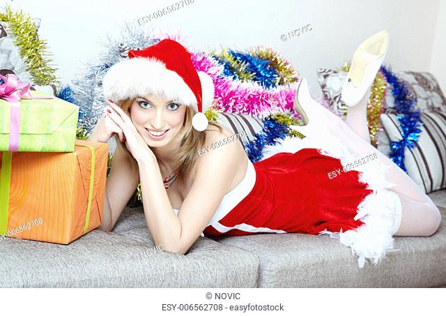 Lady in the red Santa Claus costume laying indoors near the Christmas gifts