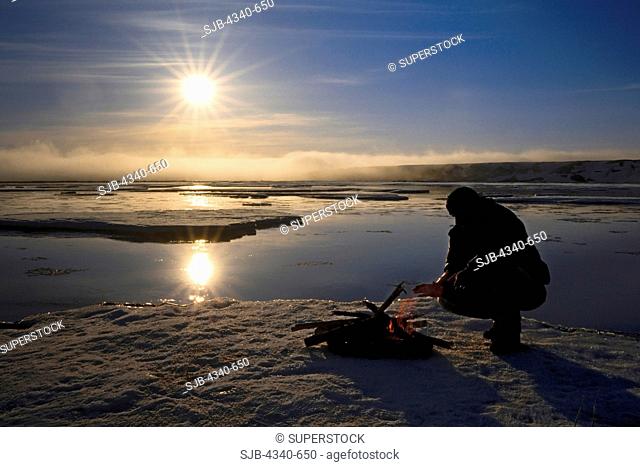 Man Making a Fire On Sea Ice Under the Midnight Sun