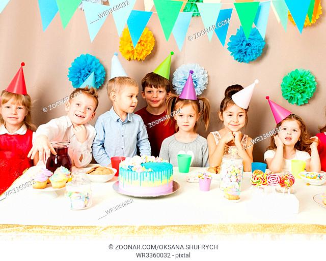 Little kids celebrating birthday. Many children near the table, friends are exciting in the hours of sweet party