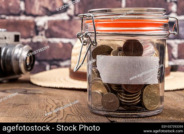 Coins in jar on wood table and brick background