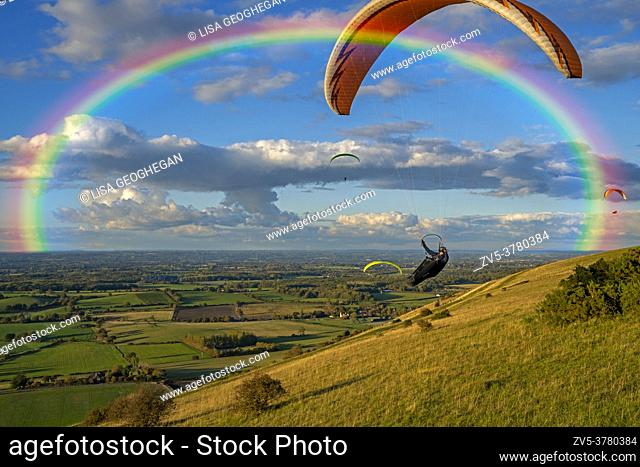 Paragliders flying underneath a rainbow on the South Downs National Park. Brighton, East Sussex. Uk