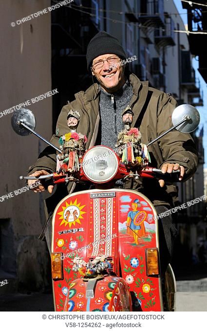 Italy, Sicily, Palermo, Artist Franco Bertolino with his painted vespa adorned with traditional sicilian marionets