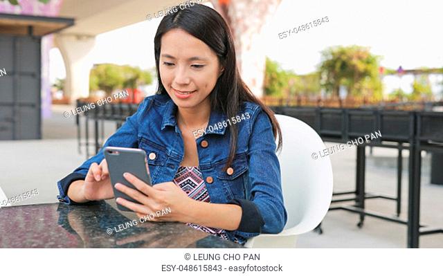 Woman using cellphone in outdoor cafe