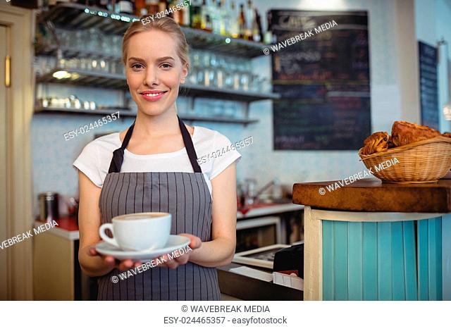Portrait of happy waitress serving beverage at cafe