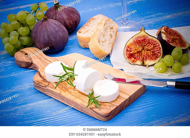 Feta cheese with ripe figs and grapes on blue, close up