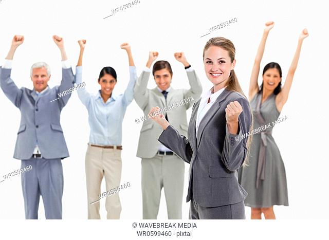 Blonde woman with business people raising their arms behind her