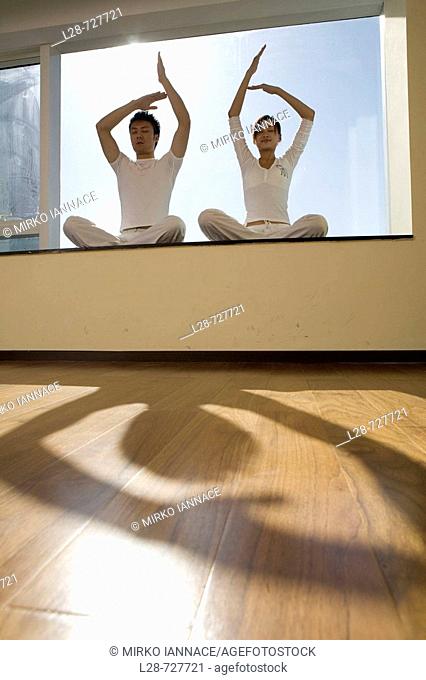 Young couple in yoga attitude indoors