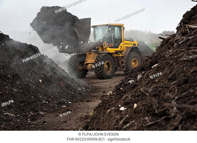 Volvo loader turning green compost waste for aeration at municipal waste site, near Chester, Cheshire, England, march