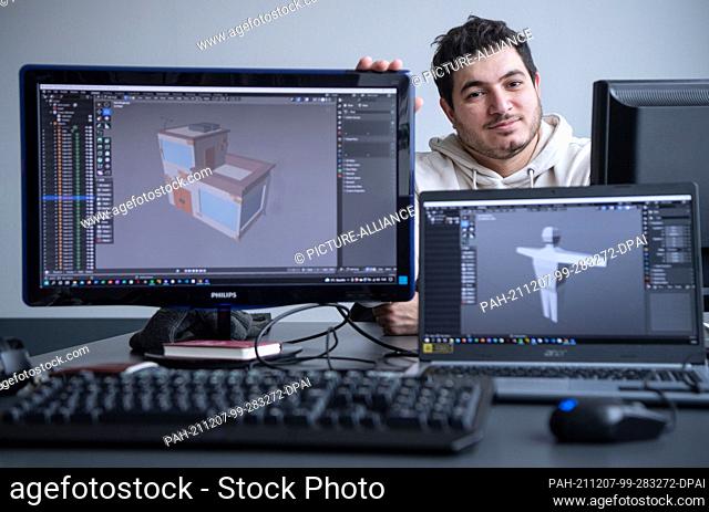 PRODUCTION - 19 November 2021, Baden-Wuerttemberg, Ludwigsburg: Rawand Ahmad, computer game developer, sits behind computer monitors showing a modelled house...