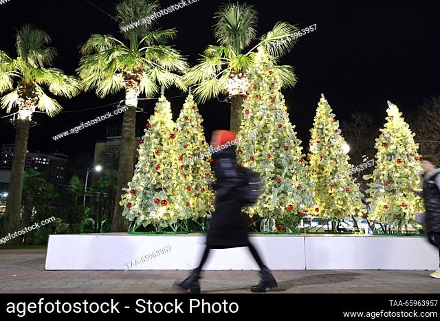 RUSSIA, SOCHI - 21 de diciembre de 2023: Una mujer se precipita más allá de los árboles de Navidad en la calle Gorky. Dmitry Feoktistov/TASS