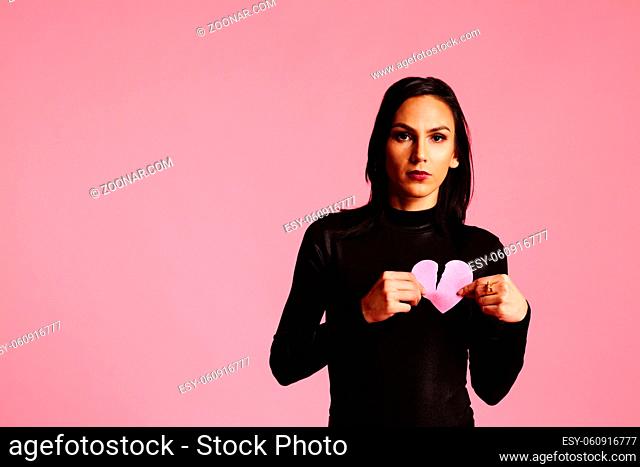 Woman holding a ripped, broken pink heart