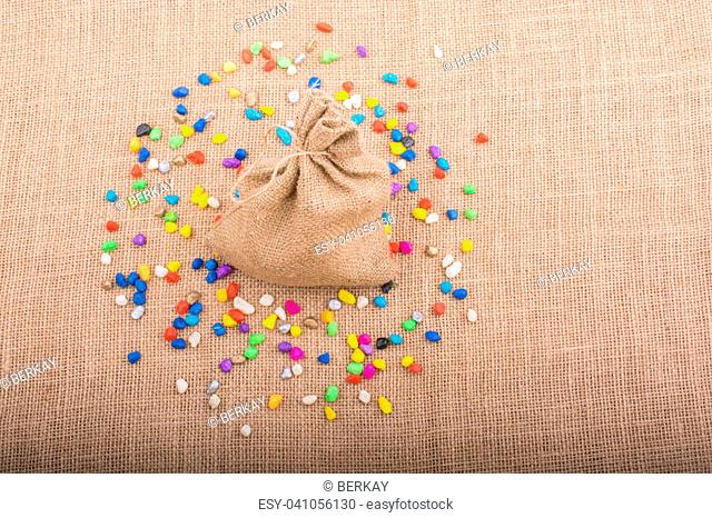 Little sack amid colorful pebbles spread on canvas