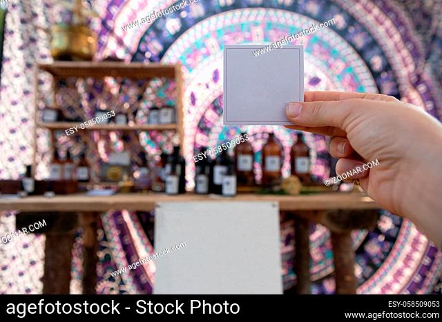 A close up shot with selective focus of a person holding an empty white sign, with copy space against a stall with handmade natural products for sale