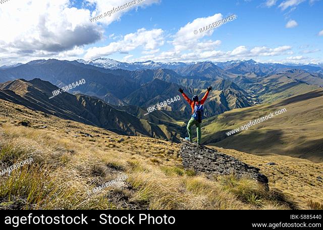 Hiker stretches out his arms in the air, hiking trail to Ben Lomond, views of mountains, Southern Alps, Otago, South Island, New Zealand, Oceania